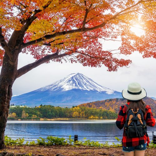 Woman traveler with backpack looking to Fuji mountains in Autumn, Japan.